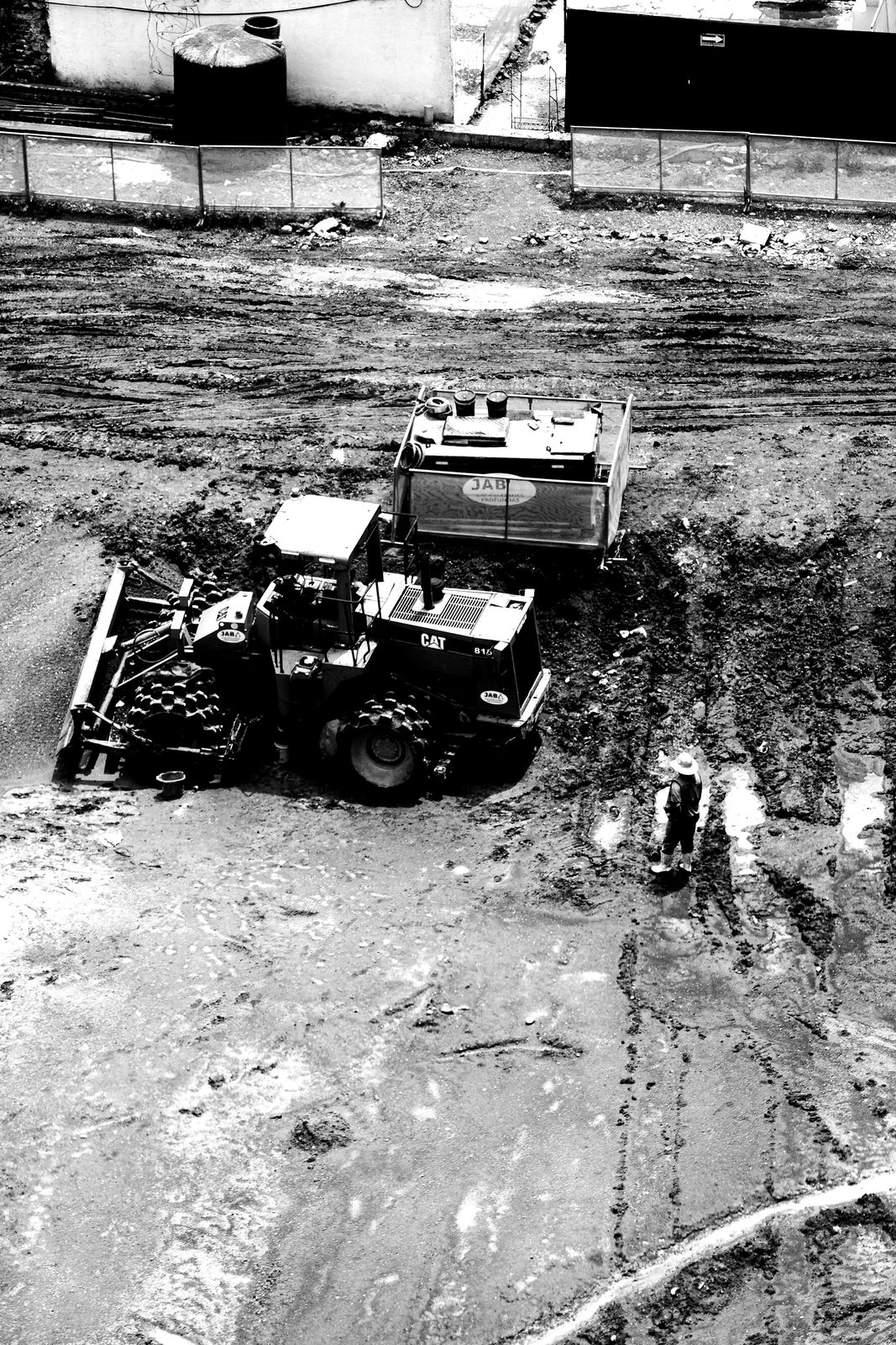 A site worker standing beside heavy plant on graded ground.