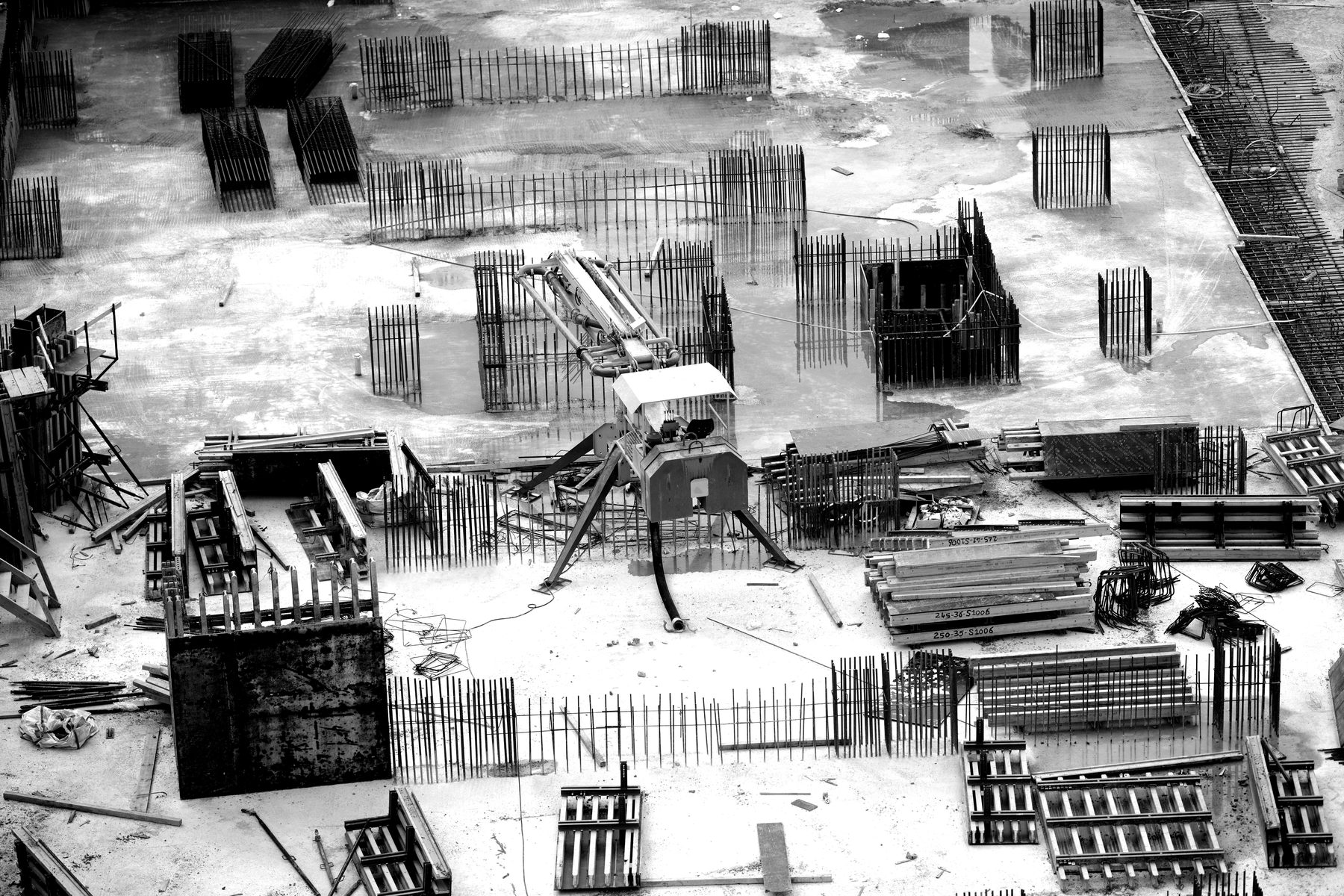 Overhead view of a concrete slab with reinforcement bars and formwork laid out in sequence.